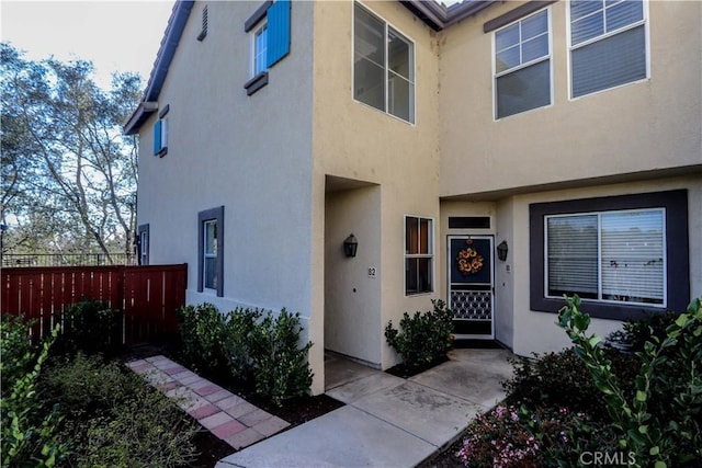 doorway to property with fence and stucco siding