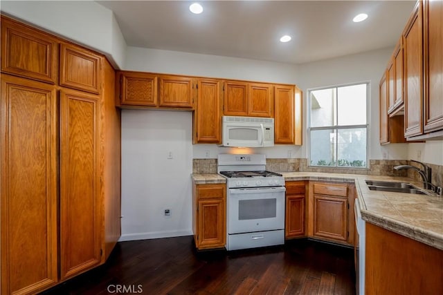 kitchen featuring brown cabinets, white appliances, dark wood finished floors, and a sink