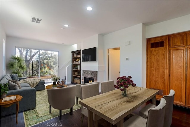 dining room with dark wood-style floors, a fireplace, visible vents, and recessed lighting