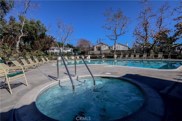 community pool featuring fence, a community hot tub, and a patio