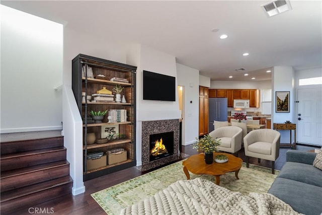 living room with dark wood-style floors, a fireplace, recessed lighting, visible vents, and stairway