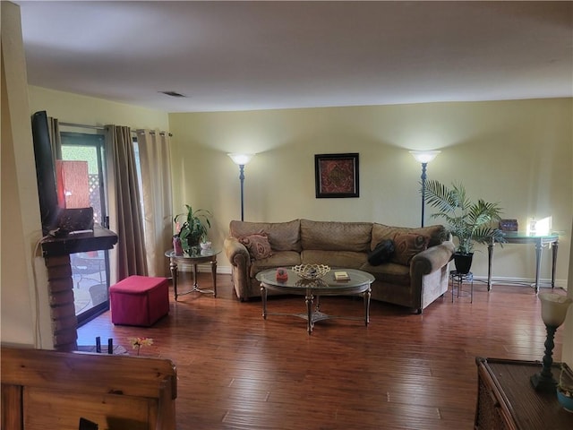 living room with dark wood-style floors, visible vents, and baseboards