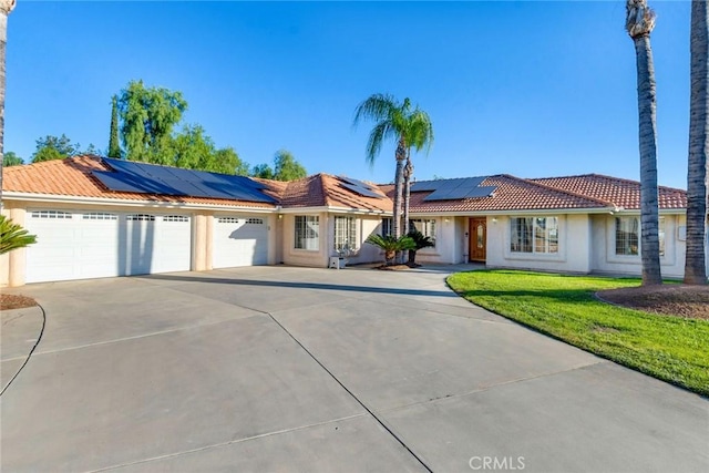 view of front of property with stucco siding, concrete driveway, a front yard, a garage, and a tiled roof