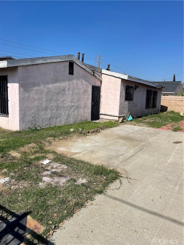 view of property exterior featuring a patio area, fence, and stucco siding