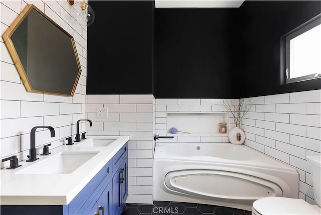 full bathroom with double vanity, a garden tub, tile walls, and a sink