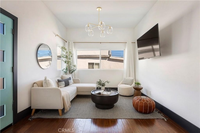 sitting room with baseboards, wood-type flooring, and an inviting chandelier