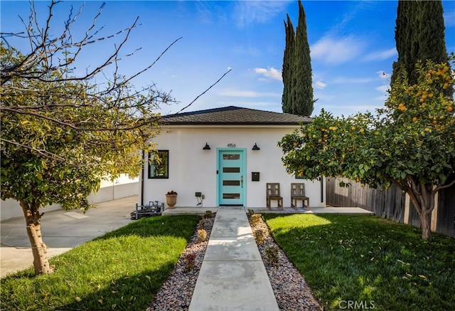 view of front of property with a front yard, fence, and stucco siding