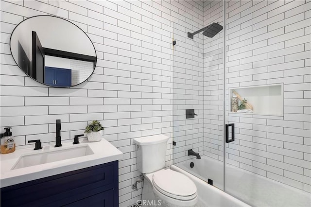 bathroom featuring enclosed tub / shower combo, vanity, toilet, and tile walls