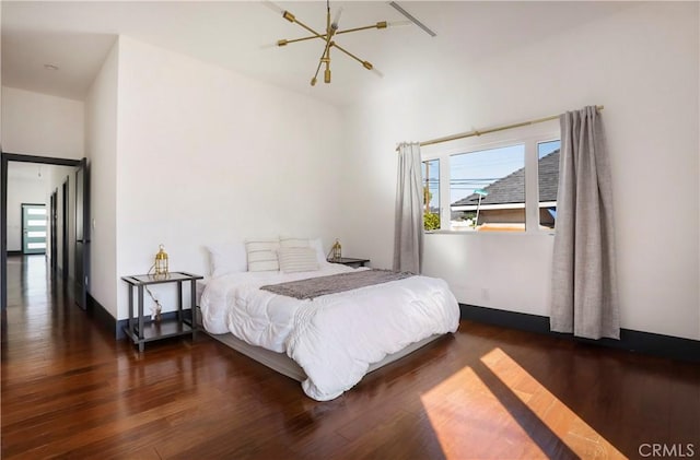 bedroom featuring a chandelier and dark wood-style flooring