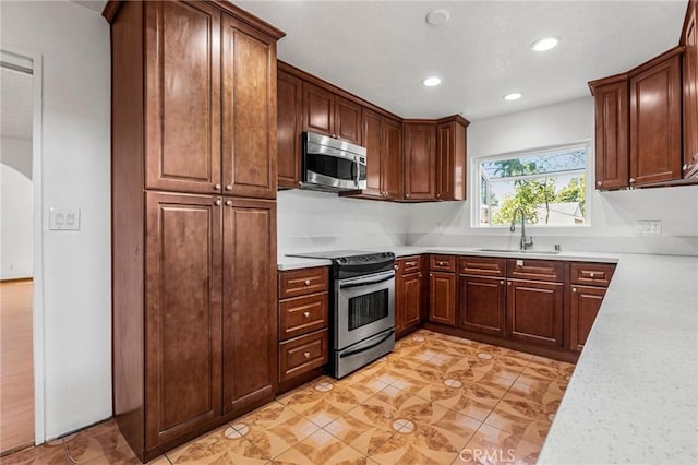 kitchen featuring arched walkways, stainless steel appliances, light countertops, a sink, and recessed lighting