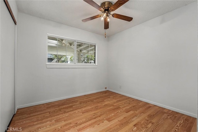 empty room featuring ceiling fan, light wood-style flooring, and baseboards