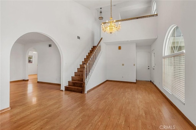 entryway featuring a towering ceiling, baseboards, arched walkways, and wood finished floors