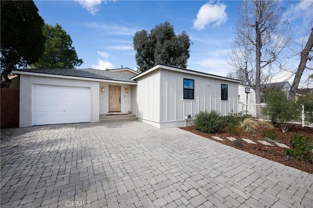 view of front facade with a garage, decorative driveway, fence, and board and batten siding