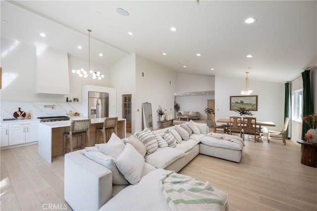 living area featuring light wood finished floors, a chandelier, high vaulted ceiling, and recessed lighting