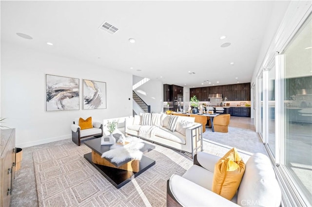 living area with recessed lighting, visible vents, baseboards, and stairs