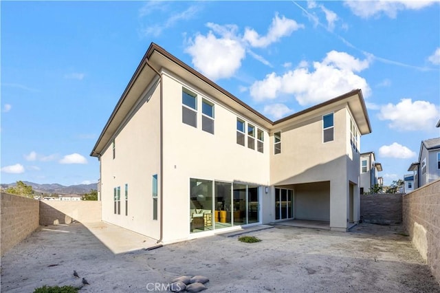 back of house with a patio area, a fenced backyard, and stucco siding