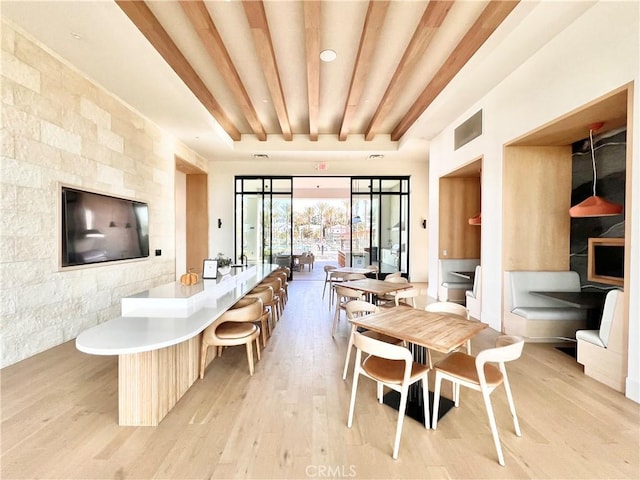 dining space with visible vents, light wood finished floors, and beam ceiling