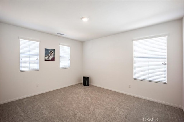 empty room with baseboards, visible vents, and carpet flooring