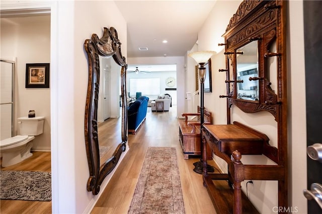 corridor featuring light wood-type flooring, visible vents, baseboards, and recessed lighting