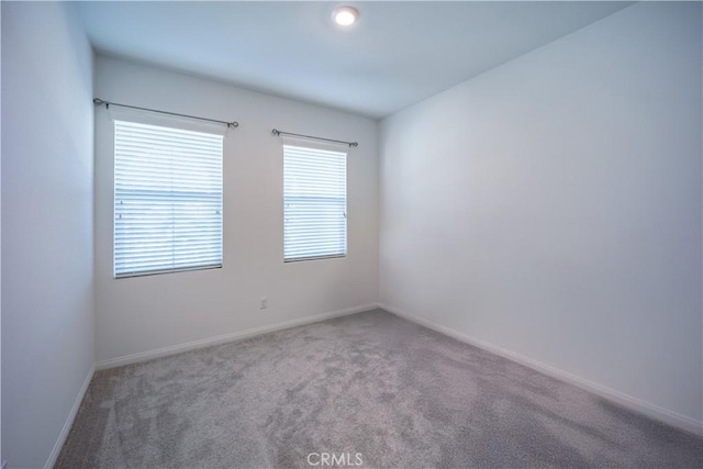 unfurnished room featuring carpet and baseboards