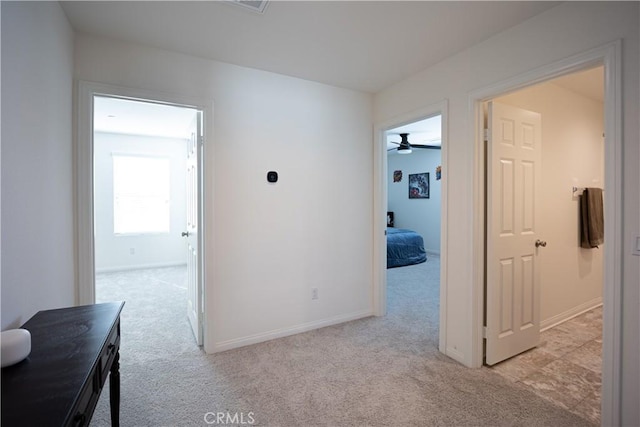 hallway featuring light carpet and baseboards