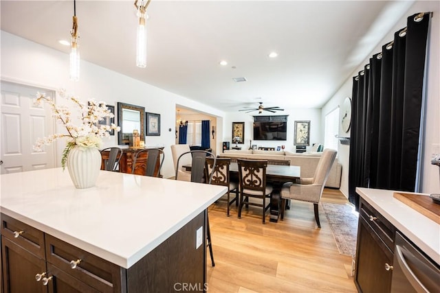 kitchen with open floor plan, hanging light fixtures, light countertops, and dark brown cabinetry