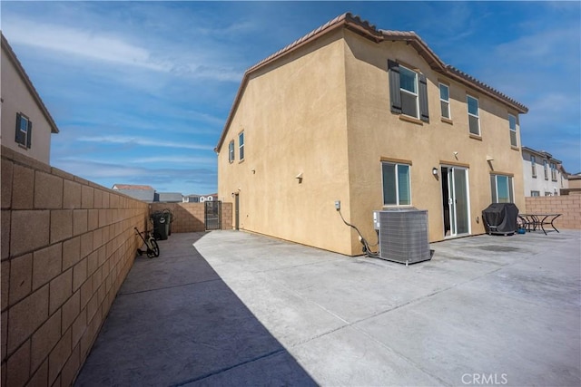 rear view of house featuring a patio area, a fenced backyard, central AC unit, and stucco siding