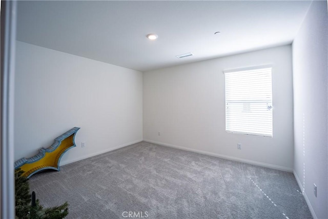 carpeted spare room featuring visible vents and baseboards