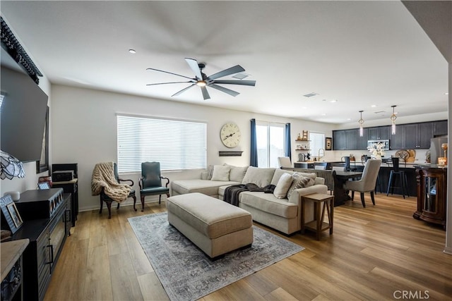 living area with recessed lighting, a ceiling fan, and light wood-style floors