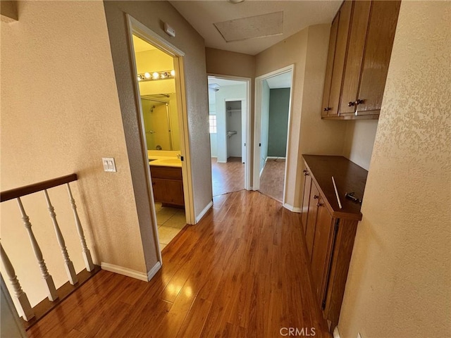 hall featuring attic access, light wood-style flooring, and baseboards