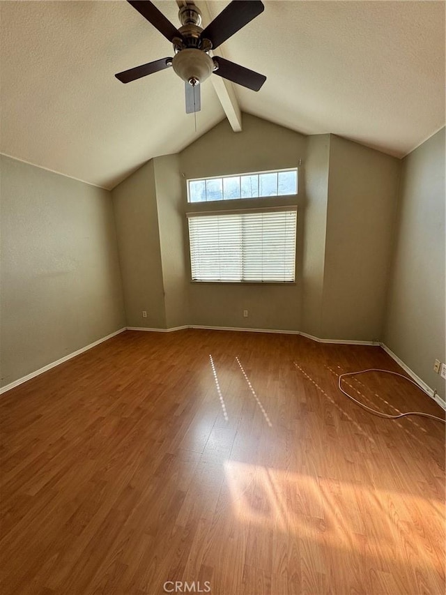 unfurnished room with ceiling fan, vaulted ceiling with beams, baseboards, and wood finished floors