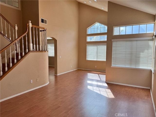 interior space featuring arched walkways, a wealth of natural light, wood finished floors, and visible vents