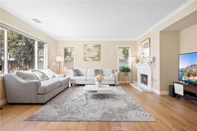 living area with light wood-style floors, a premium fireplace, visible vents, and crown molding