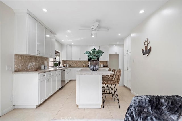 kitchen with tasteful backsplash, a breakfast bar area, white cabinets, and stainless steel dishwasher