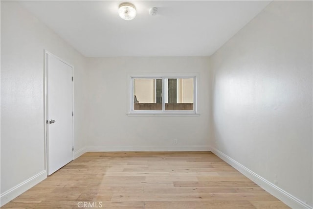 spare room featuring light wood finished floors and baseboards