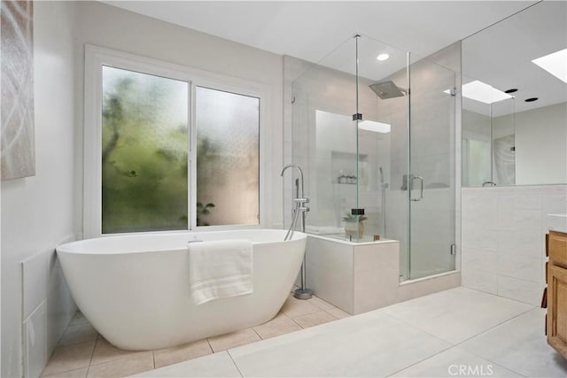 full bath featuring tile patterned flooring, vanity, a freestanding tub, a shower stall, and tile walls