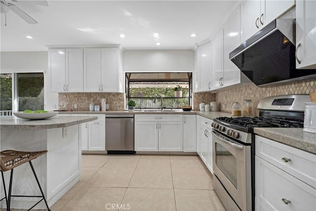 kitchen featuring light tile patterned floors, stainless steel appliances, tasteful backsplash, a sink, and ventilation hood