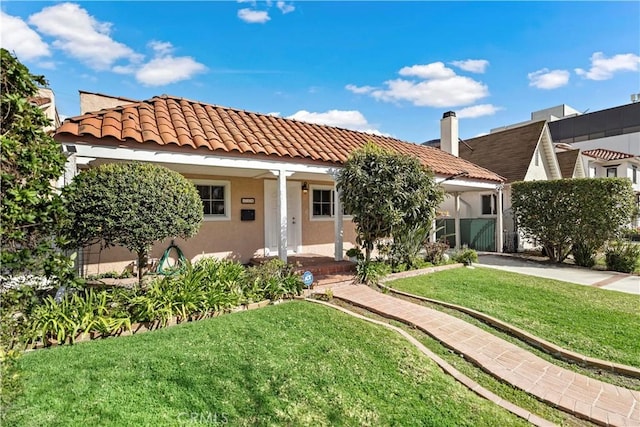 view of front of property with a tiled roof, a front lawn, and stucco siding