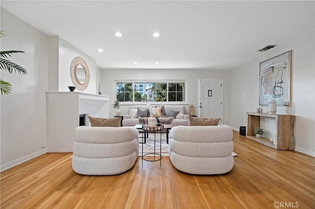 living room with recessed lighting, visible vents, a fireplace, and wood finished floors