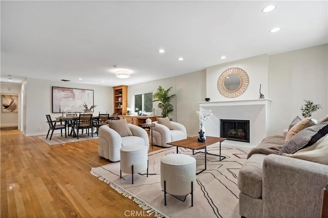 living area with baseboards, a fireplace, light wood-style flooring, and recessed lighting