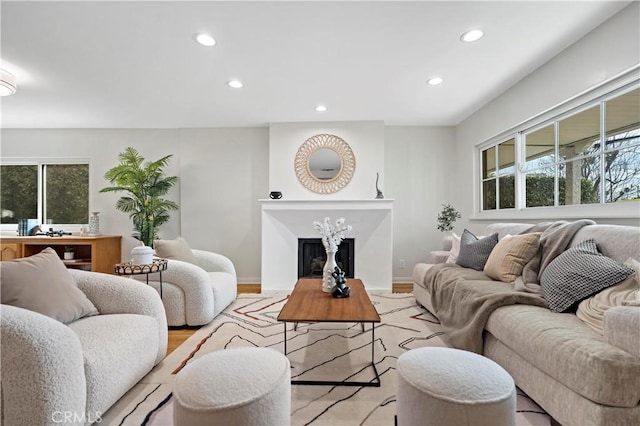 living room featuring a high end fireplace, recessed lighting, baseboards, and wood finished floors