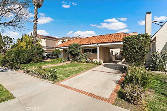 mediterranean / spanish house with a tile roof, stucco siding, concrete driveway, an attached carport, and a front lawn