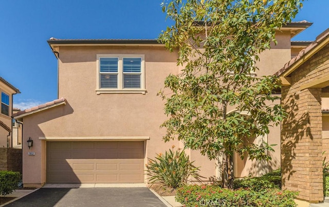 view of front of house featuring an attached garage, a tiled roof, concrete driveway, and stucco siding