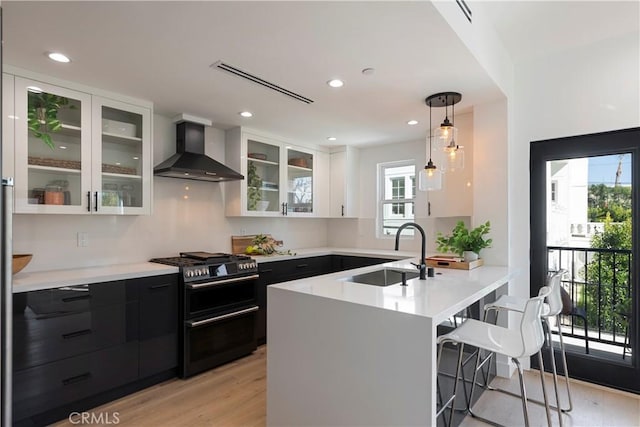 1903 N Stoke Ln, Los Angeles, CA 90068 - kitchen with wall chimney exhaust hood, a sink, range with two ovens, dark cabinets, and light countertops