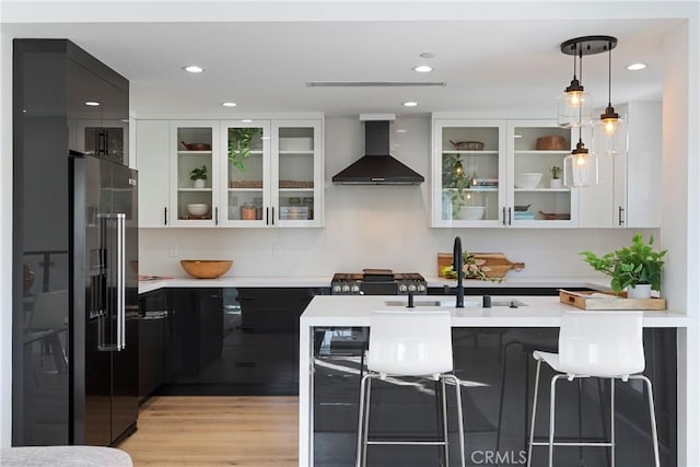 1903 N Stoke Ln, Los Angeles, CA 90068 - kitchen featuring wall chimney exhaust hood, black fridge, dark cabinets, light countertops, and recessed lighting