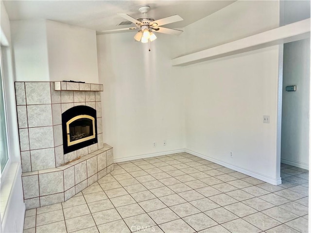 unfurnished living room with ceiling fan, a fireplace, light tile patterned flooring, and baseboards