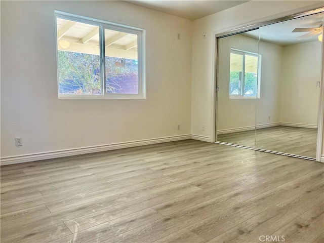 unfurnished room with ceiling fan, light wood-type flooring, and baseboards