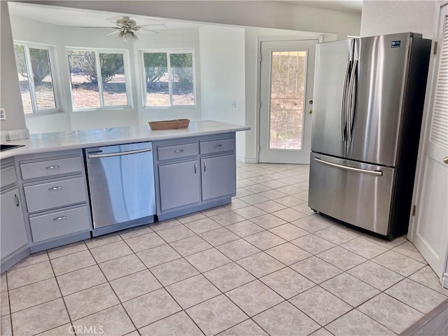 kitchen with light countertops, gray cabinetry, appliances with stainless steel finishes, light tile patterned flooring, and ceiling fan