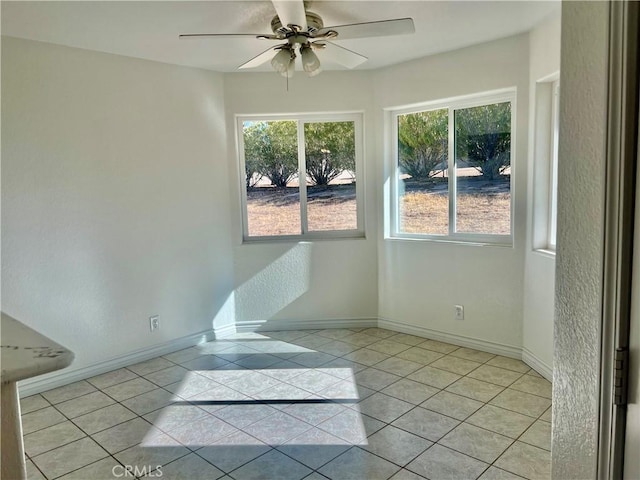 unfurnished room featuring ceiling fan, baseboards, and light tile patterned floors