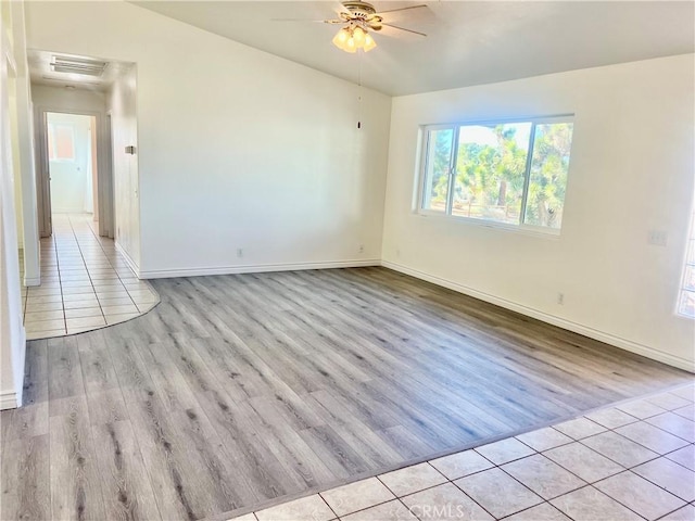 unfurnished room featuring baseboards, light wood finished floors, visible vents, and a ceiling fan